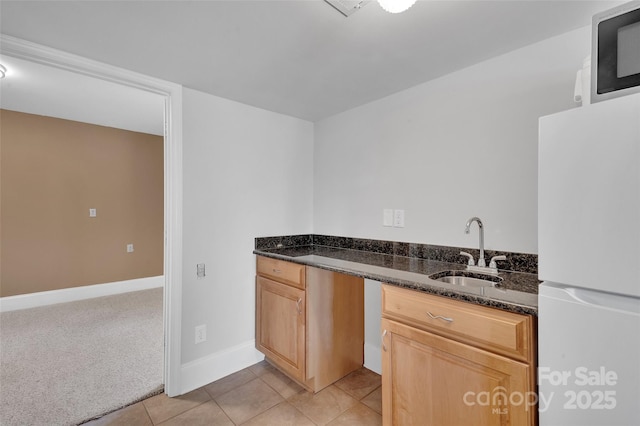 1077 Gauguin Ln, Tega Cay, SC 29708 - kitchen with freestanding refrigerator, a sink, dark stone counters, light tile patterned floors, and baseboards