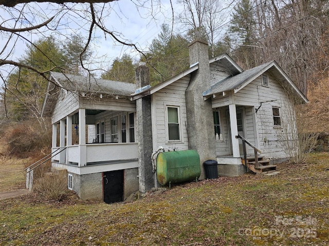 view of front of home with entry steps, a chimney, and heating fuel