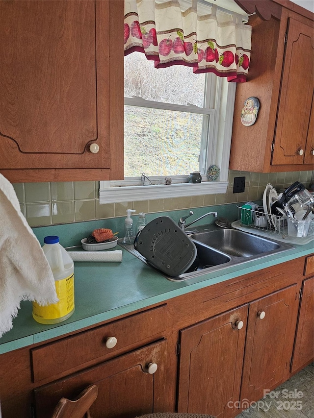 kitchen with light countertops, brown cabinetry, a sink, and decorative backsplash