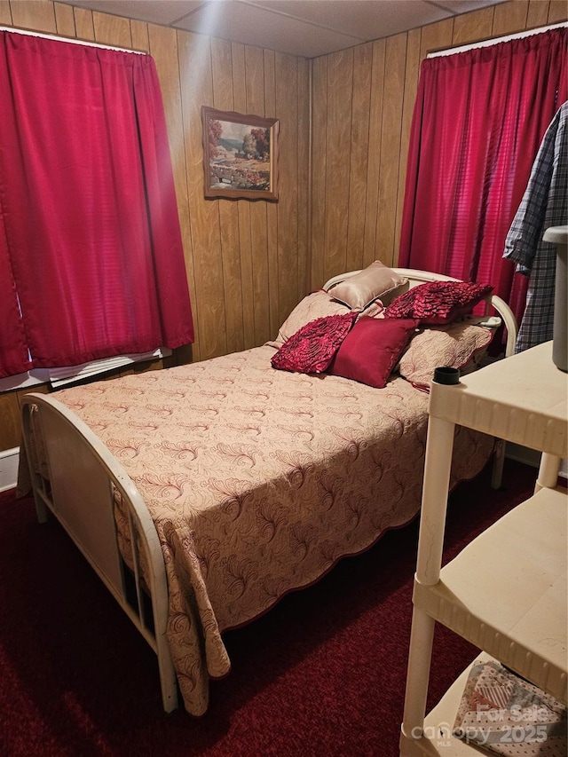 bedroom featuring wood walls and dark carpet