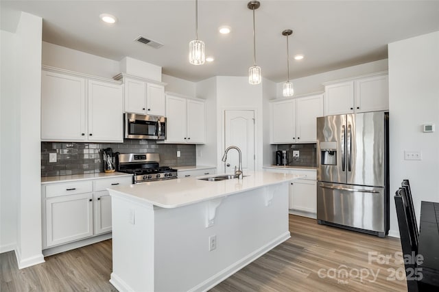 kitchen with stainless steel appliances, sink, hanging light fixtures, and white cabinets