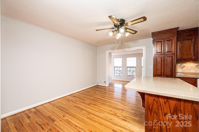 unfurnished living room with ceiling fan, light hardwood / wood-style floors, and a textured ceiling