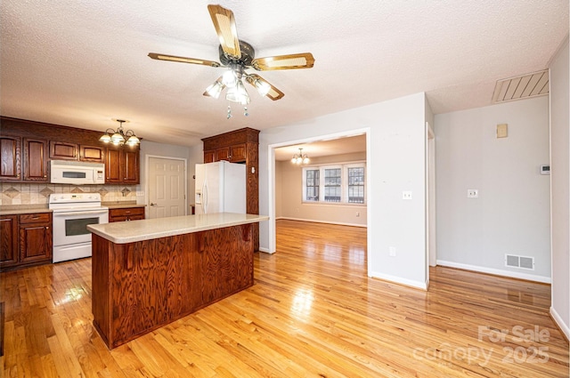 kitchen with tasteful backsplash, a center island, light hardwood / wood-style flooring, a textured ceiling, and white appliances