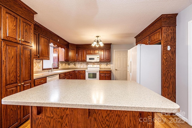 kitchen featuring an inviting chandelier, white appliances, a center island, and decorative backsplash