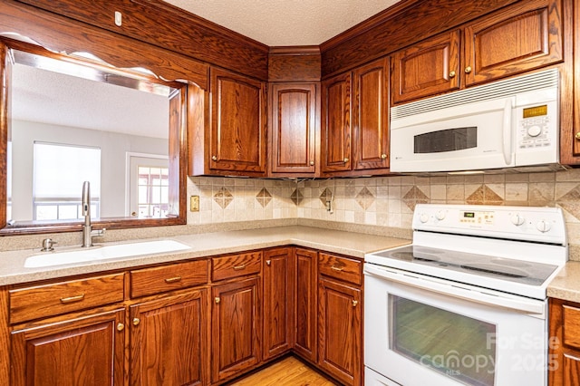 kitchen with sink, light hardwood / wood-style flooring, a textured ceiling, white appliances, and decorative backsplash