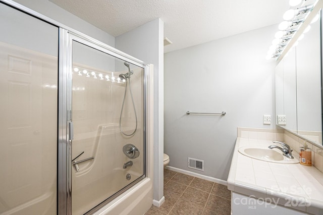 full bathroom featuring combined bath / shower with glass door, tile patterned flooring, vanity, toilet, and a textured ceiling