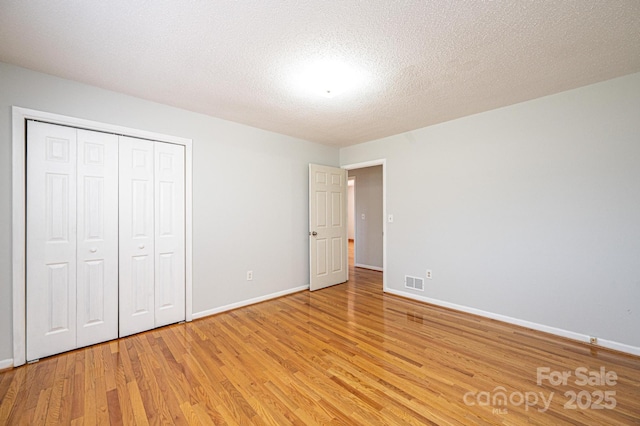 unfurnished bedroom featuring light hardwood / wood-style floors, a closet, and a textured ceiling