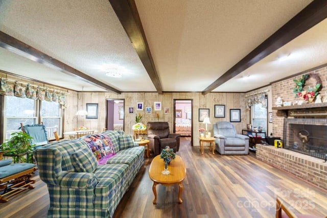 living room featuring dark wood-type flooring, beam ceiling, wood walls, a textured ceiling, and a fireplace