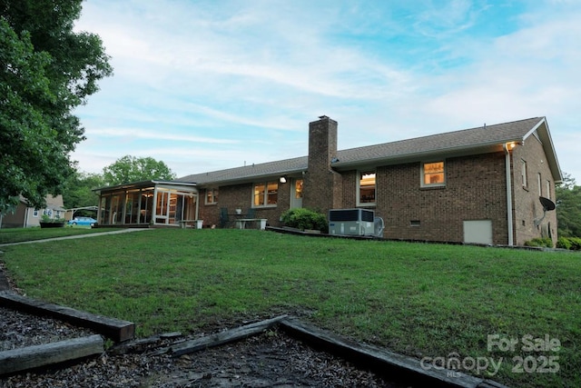 4816 Zion Church Rd, Concord, NC 28025 - rear view of property featuring a chimney, a sunroom, brick siding, a lawn, and cooling unit