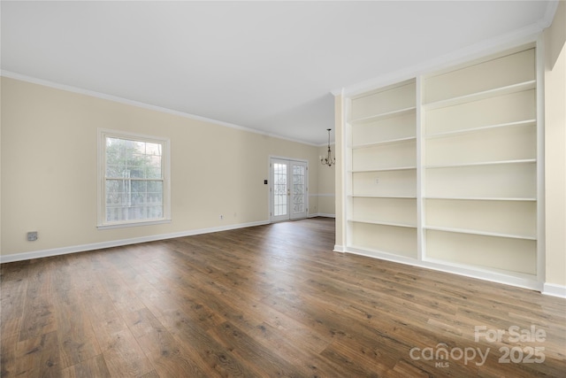 spare room featuring crown molding, dark wood-type flooring, a notable chandelier, and french doors