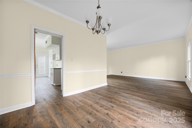 empty room featuring crown molding, dark hardwood / wood-style flooring, a chandelier, and a wealth of natural light