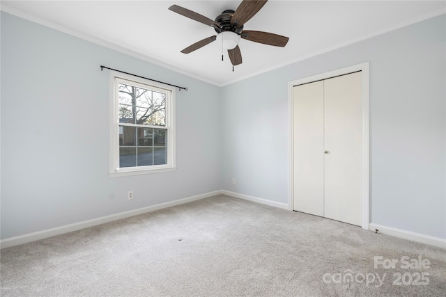 unfurnished bedroom with ornamental molding, light colored carpet, ceiling fan, and a closet