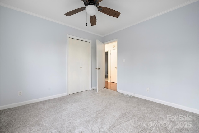 unfurnished bedroom featuring crown molding, light carpet, ceiling fan, and a closet