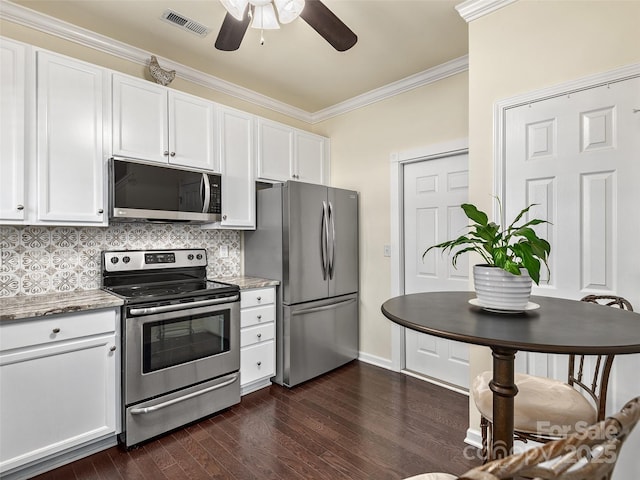 kitchen with crown molding, dark wood-type flooring, white cabinetry, stainless steel appliances, and light stone countertops