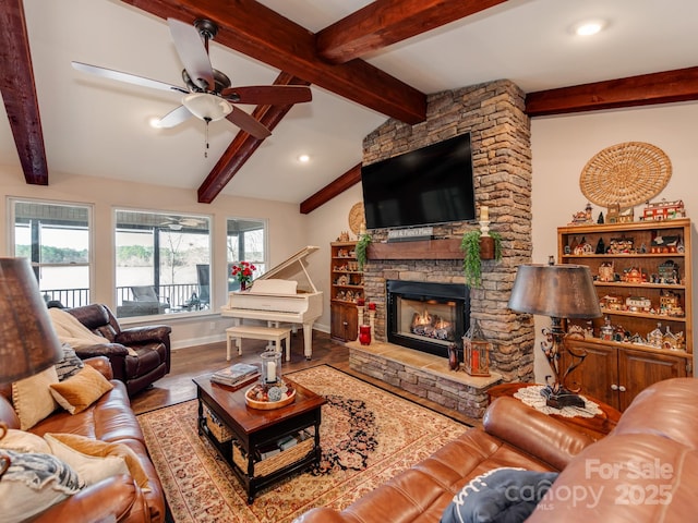 living room with hardwood / wood-style flooring, ceiling fan, lofted ceiling with beams, and a stone fireplace