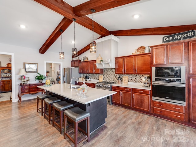 kitchen with a center island with sink, appliances with stainless steel finishes, a breakfast bar, and decorative light fixtures