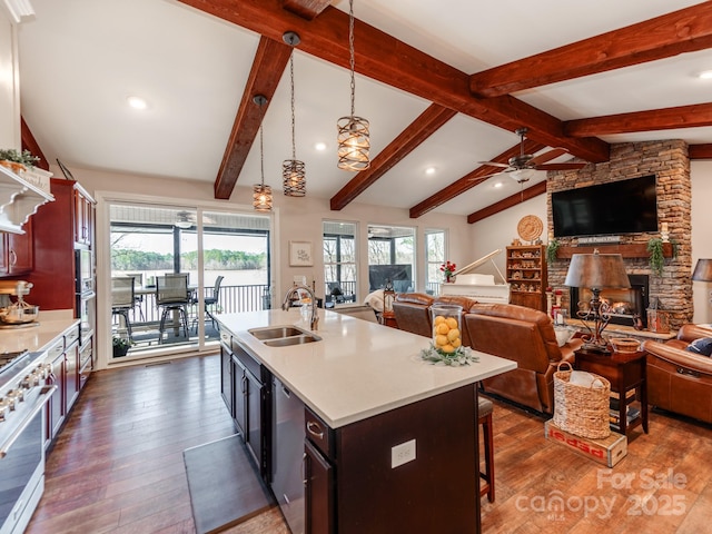 kitchen with decorative light fixtures, gas range, a fireplace, sink, and a kitchen island with sink