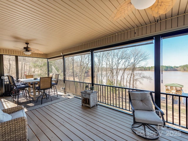 sunroom with ceiling fan and a water view