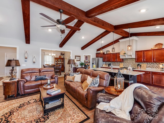 living room featuring light wood-type flooring, lofted ceiling with beams, and ceiling fan with notable chandelier