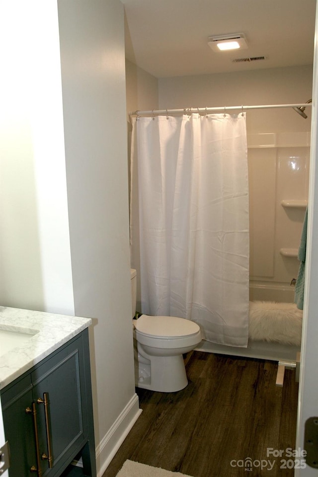 bathroom with hardwood / wood-style flooring, vanity, toilet, and walk in shower