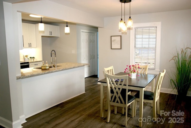 kitchen with sink, white cabinetry, decorative light fixtures, dark hardwood / wood-style flooring, and light stone countertops