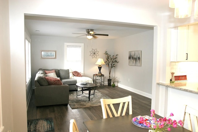 living room with dark wood-type flooring and ceiling fan