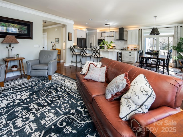 living room with hardwood / wood-style flooring, crown molding, sink, and wine cooler