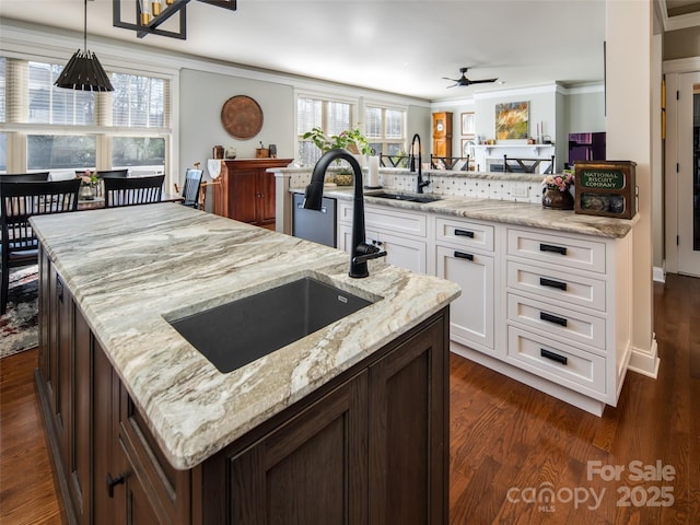 kitchen featuring sink, dark wood-type flooring, light stone counters, white cabinets, and decorative light fixtures