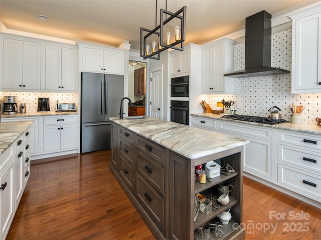 kitchen with stainless steel appliances, white cabinetry, wall chimney range hood, and decorative light fixtures