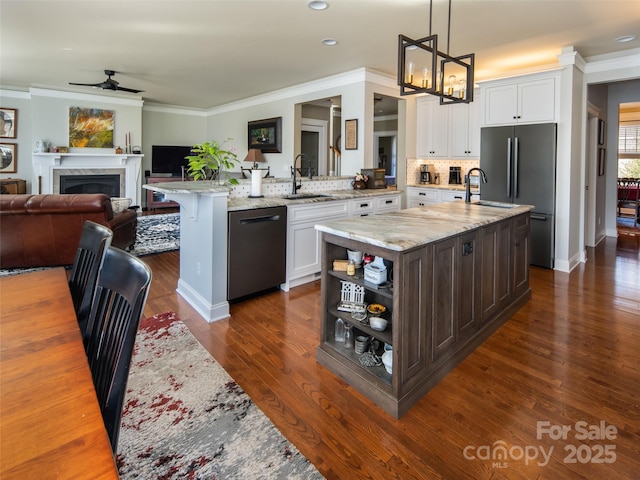 kitchen featuring pendant lighting, an island with sink, black dishwasher, a breakfast bar area, and white cabinets