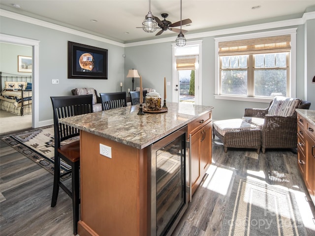 kitchen with a breakfast bar area, ornamental molding, a kitchen island, decorative light fixtures, and beverage cooler