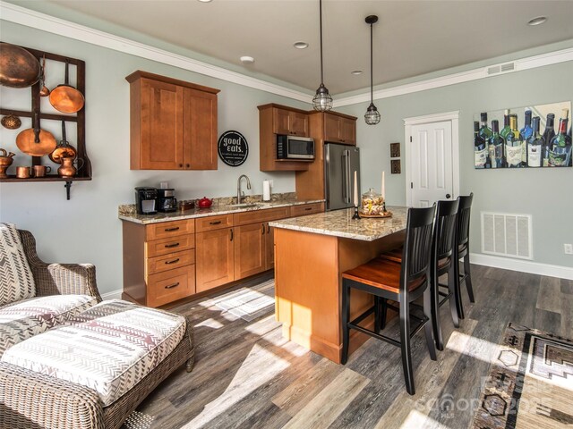 kitchen featuring hanging light fixtures, ornamental molding, stainless steel appliances, and a center island