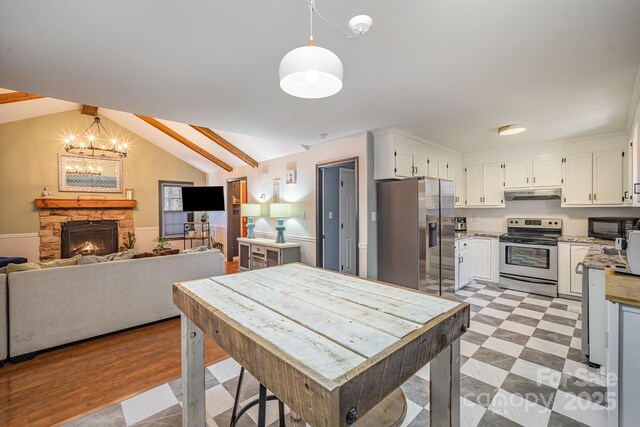 kitchen with a fireplace, decorative light fixtures, white cabinetry, stainless steel appliances, and an inviting chandelier