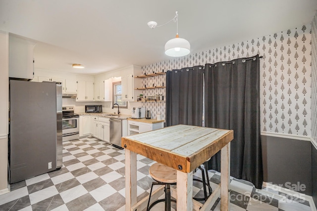 kitchen with white cabinetry, appliances with stainless steel finishes, decorative light fixtures, and sink