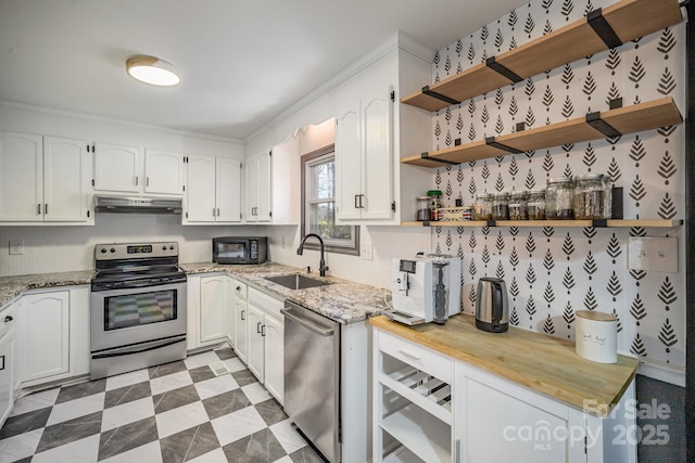 kitchen with stainless steel appliances, light stone countertops, sink, and white cabinets