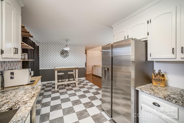 kitchen featuring white cabinetry, stainless steel fridge, and light stone countertops