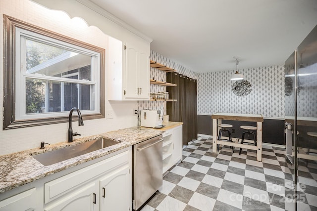 kitchen with hanging light fixtures, white cabinetry, sink, and stainless steel dishwasher