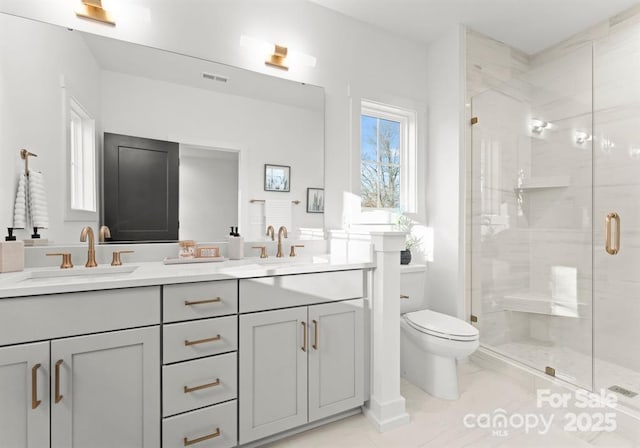 bathroom with a stall shower, double vanity, and toilet