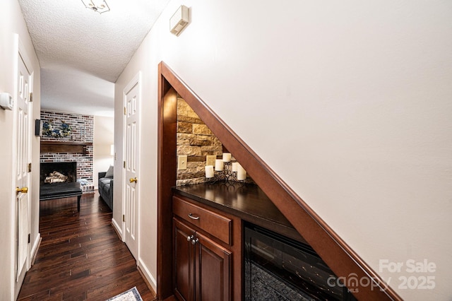 bar with dark hardwood / wood-style floors, beverage cooler, a fireplace, and a textured ceiling