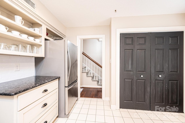 kitchen featuring light tile patterned floors, decorative backsplash, and stainless steel fridge