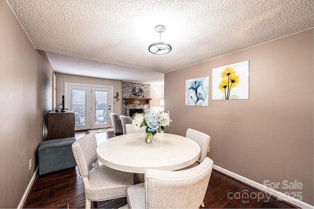 dining area featuring dark hardwood / wood-style floors, a fireplace, and a textured ceiling