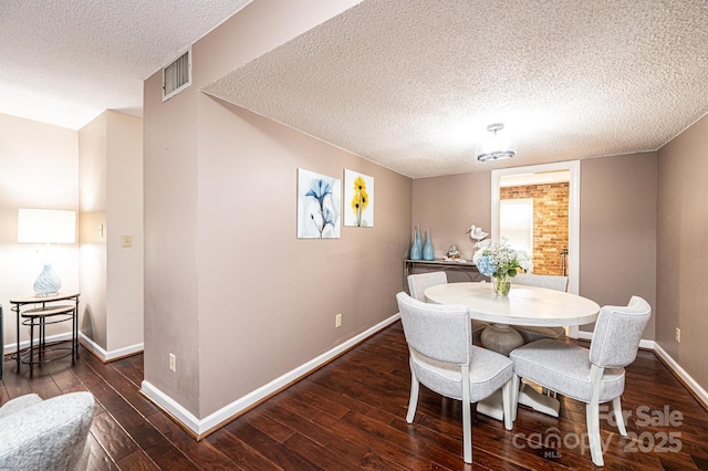 dining room with dark wood-type flooring and a textured ceiling