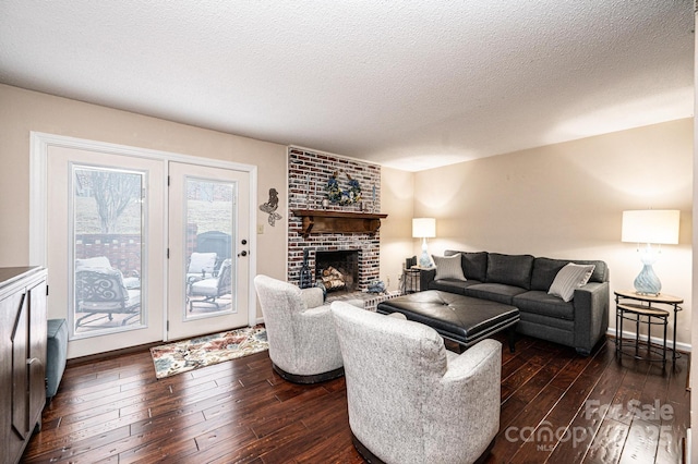 living room featuring a brick fireplace, dark wood-type flooring, and a textured ceiling