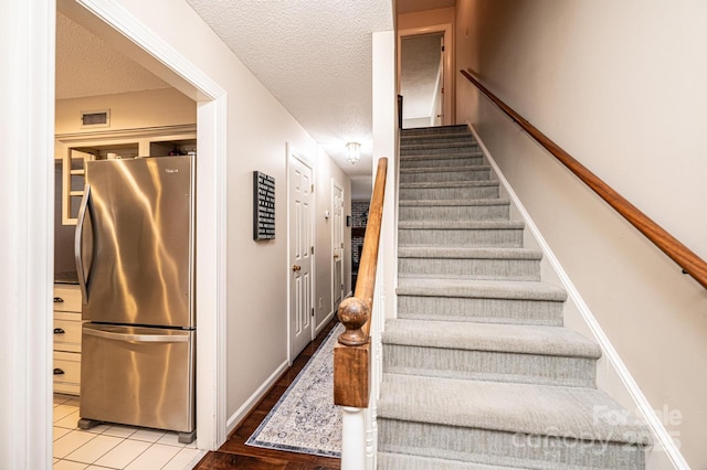 staircase featuring a textured ceiling