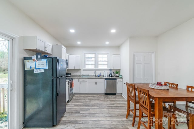 kitchen with sink, light hardwood / wood-style floors, white cabinets, and appliances with stainless steel finishes