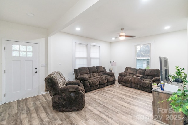 living room featuring ceiling fan, beam ceiling, and light wood-type flooring