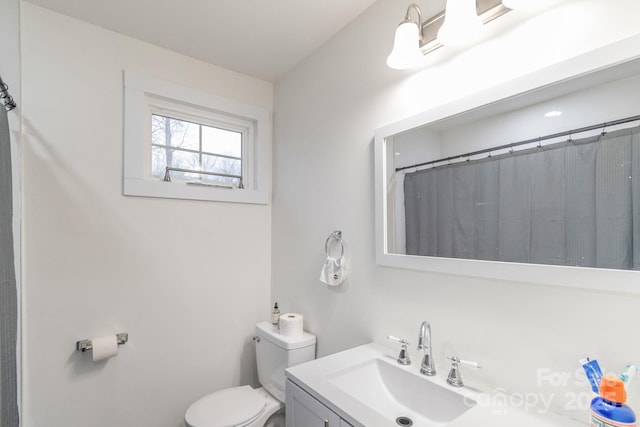 bathroom featuring vanity, walk in shower, and toilet