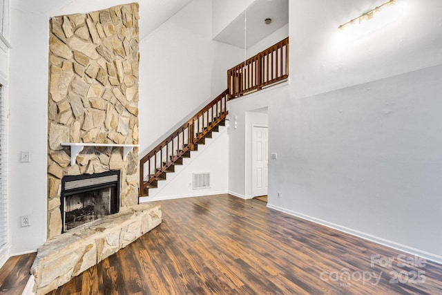 unfurnished living room featuring a high ceiling, dark hardwood / wood-style floors, and a fireplace