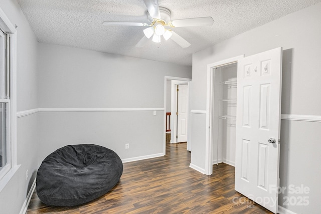 living area with ceiling fan, dark hardwood / wood-style floors, and a textured ceiling