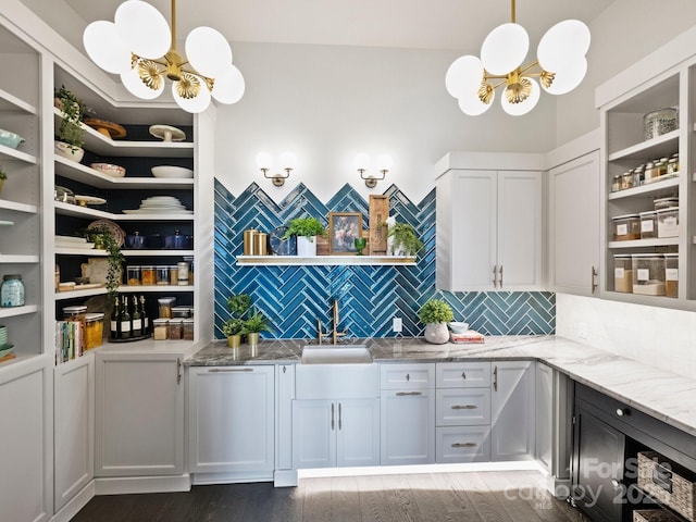 interior space with sink, white cabinets, a chandelier, hanging light fixtures, and light stone counters